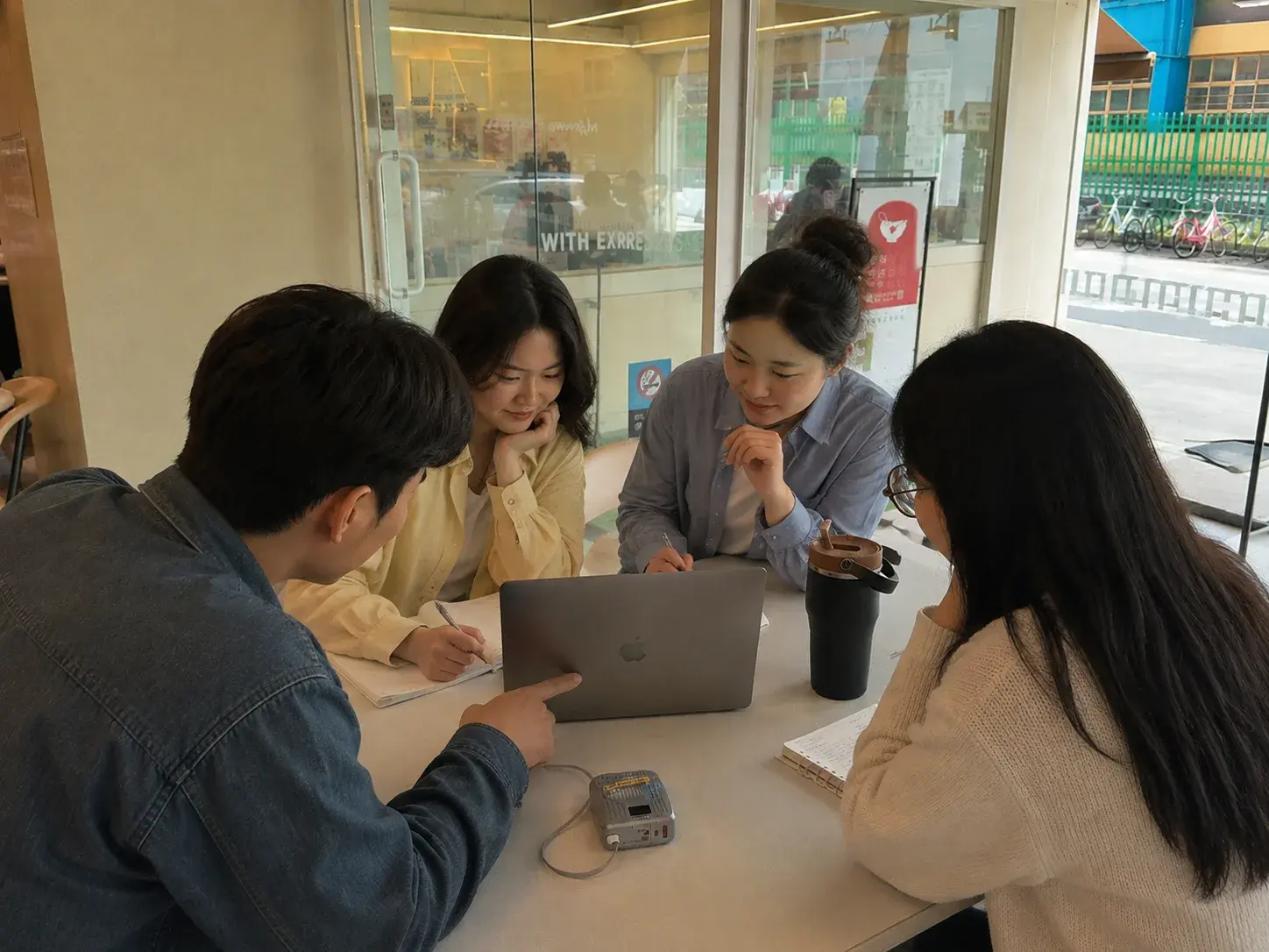 신입 구성원들이 노트북 화면을 함께 보며 한 사람이 화면을 가리키는 모습
